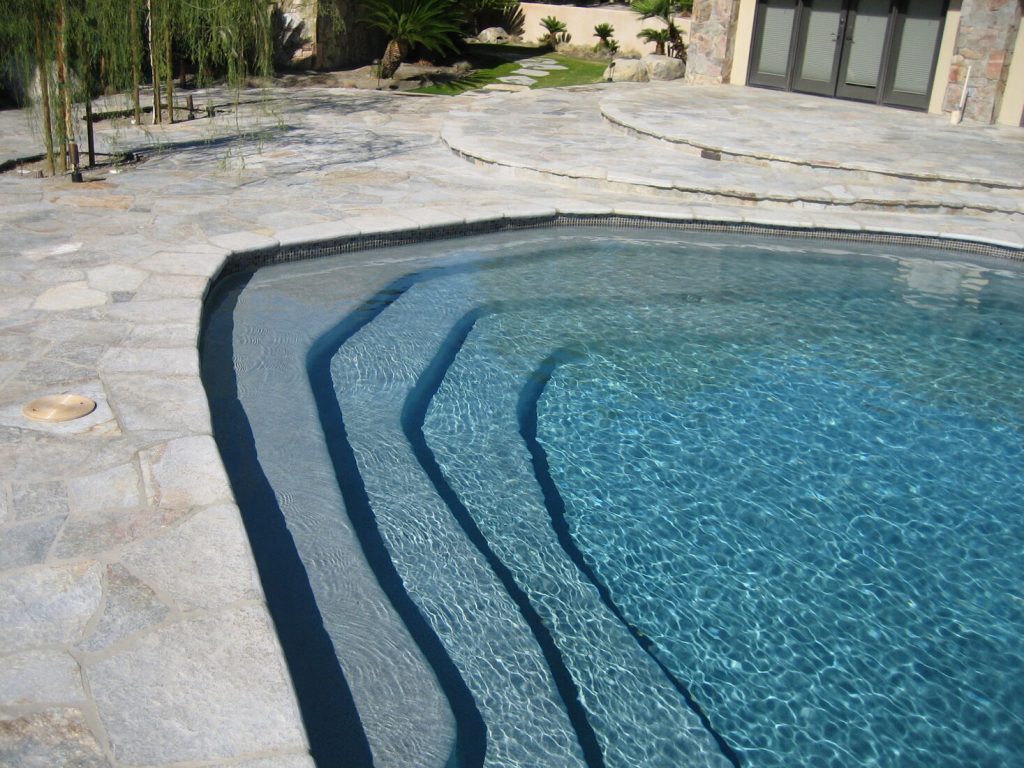 Pool remodeling with tanning ledge steps, slate tile trim, and natural stone patio
