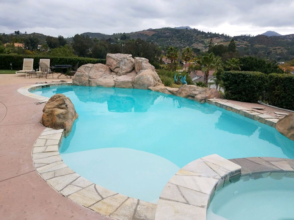 Freeform pool remodeling project with quartzite coping, natural stone, and rock waterfall slide
