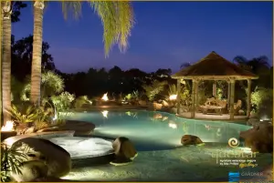 Tropical luxury pool remodeling project with illuminated hot tub, gazebo, and palm trees at dusk