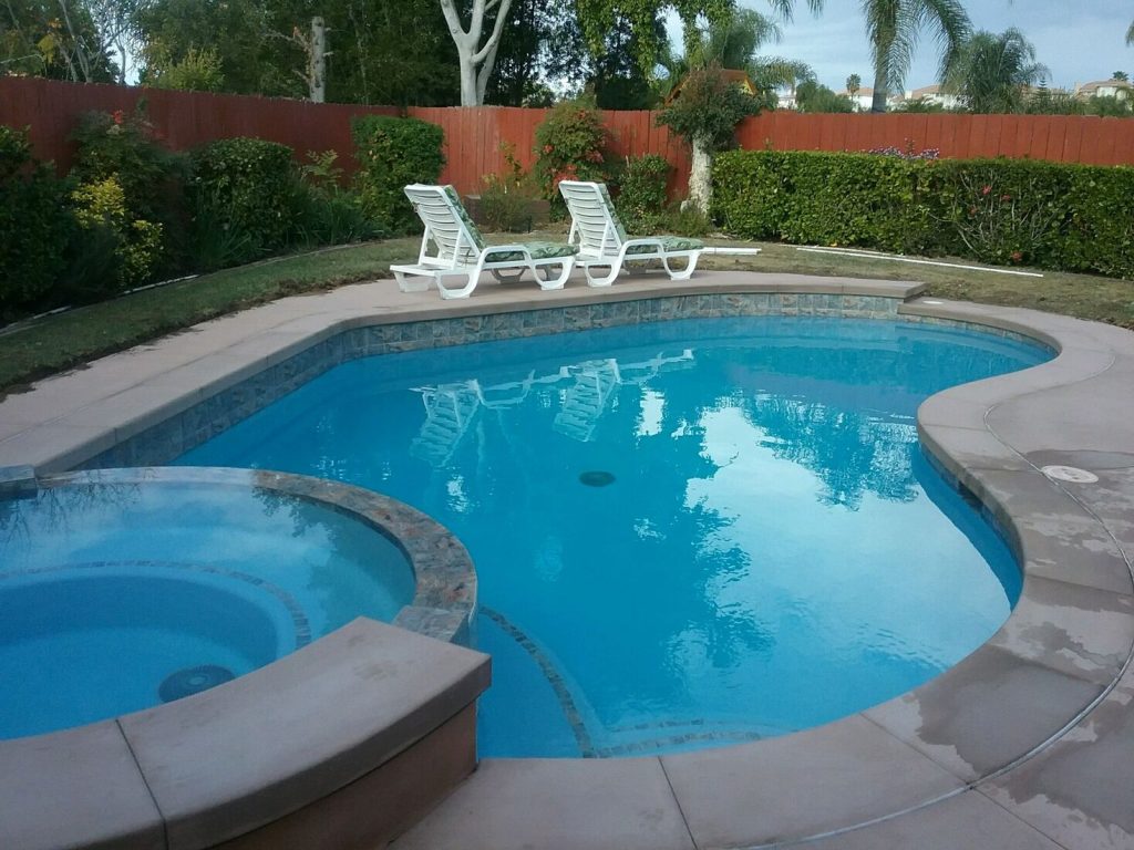 Backyard pool remodel with elevated spa, poured concrete coping, and custom decking