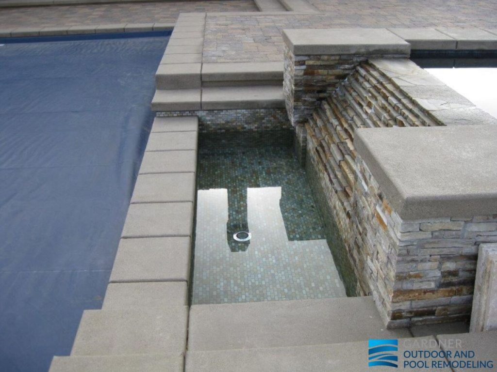Modern pool remodeling with poured-in-place concrete coping and stacked stone water feature