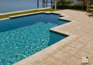 Travertine pool coping and stone patio deck surrounding a swimming pool with clear water