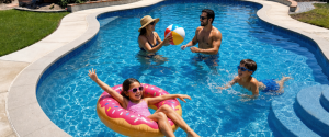 Family playing with a beach ball in a backyard swimming pool during a pool remodeling project